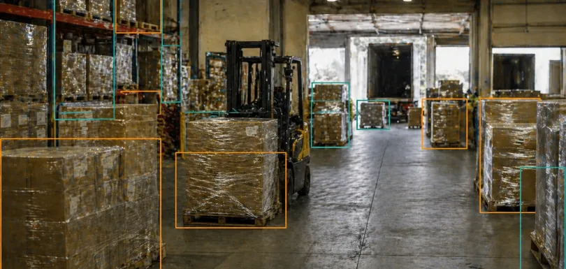 Warehouse logistics environment with pallets and goods annotated with orange and teal AI bounding boxes, representing Adarga AI's strategic AI consulting approach to improving operational efficiency and inventory management across African markets.